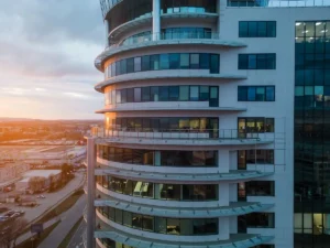 Edificio moderno de comunidad de propietarios con fachada curva y amplios ventanales que requiere correcta implementación del CAE para garantizar la seguridad en zonas comunes y cumplir la normativa vigente.