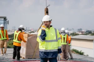 Coordinador de seguridad y salud supervisando obra de construcción con casco y chaleco