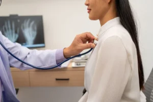 Médecin du travail ausculant un salarié avec un stéthoscope lors d'une visite de suivi individuel, dans le cadre de la législation santé au travail
