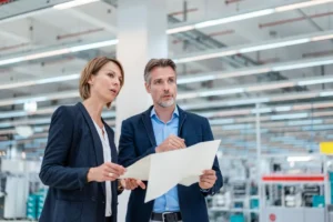 Deux professionnels analysent un plan dans un environnement industriel pour évaluer les risques professionnels dans le cadre du document unique DUERP.