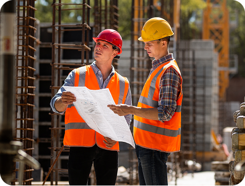 Operai edili che esaminano i disegni tecnici in cantiere