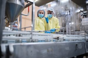 Una lavoratrice ed un lavoratore all'interno di uno stabilimento di produzione alimentare