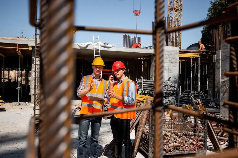 Trabajadores de construcción en obra cumpliendo NOM-031 con equipo de protección personal completo, cascos y arneses en México