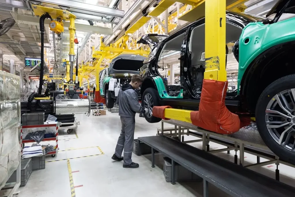 Trabalhador em linha de montagem automobilística usando equipamentos de proteção individual conforme normas de segurança e saúde no trabalho
