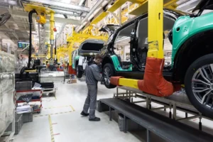Trabalhador em linha de montagem automobilística usando equipamentos de proteção individual conforme normas de segurança e saúde no trabalho