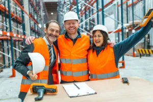 Trabalhadores felizes em ambiente seguro demonstrando a importância da segurança e saúde no trabalho para produtividade empresarial