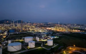 Refinaria petroquímica em Portugal com torres de destilação iluminadas e tanques de armazenamento - gestão de subcontratados e segurança SST em zonas ATEX