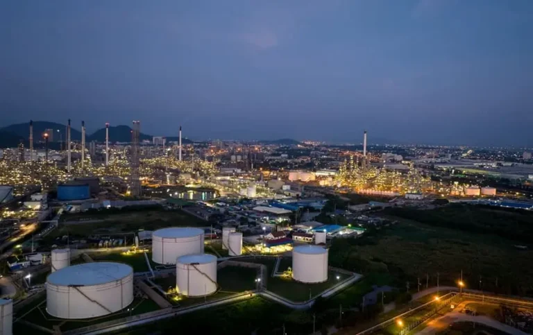 Refinaria petroquímica em Portugal com torres de destilação iluminadas e tanques de armazenamento - gestão de subcontratados e segurança SST em zonas ATEX